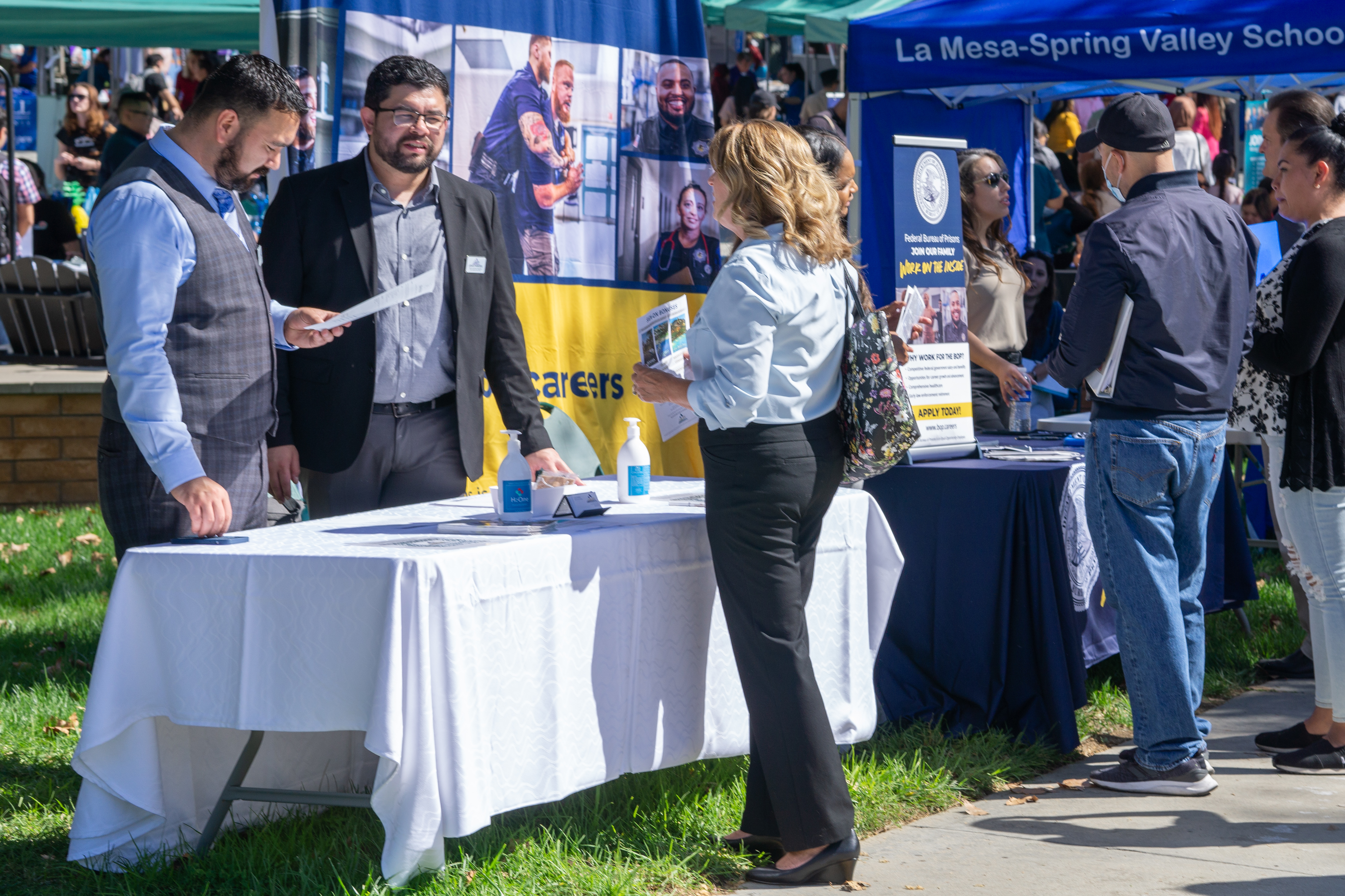 Job seeker conversing with recruiters at Grossmont College job fair.